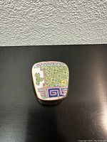 Top view showing colorful enamel top with geometric and leaf design.