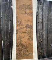 Full view of vintage Asian scroll painting hanging, showcasing mountain landscape, trees, boats, and a pavilion.