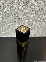 Front side view of the vintage Chanel No. 5 cologne bottle showing the iconic black and gold design with Chanel CC logo on the top of the cap.