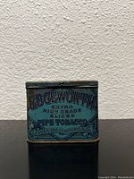 Front side of vintage Edgeworth tobacco tin showing embossed lettering and decorative design in blue and black.