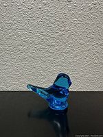 Side profile of the blue glass bird figurine showing smooth blue glass and wing details.