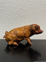 Side view of the hand carved wooden pig, showing texture and carving details.