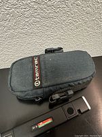Photo of Tamrac carrying case for camera, dark gray fabric with zipper and strap.