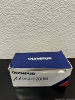 Original Olympus blue and white box showing the top and sides with branding 'μ[mju:] Zoom'. The box is slightly worn.