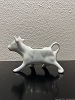 Side profile of the white porcelain cow-shaped milk spout showing detailed shape and hollow body.