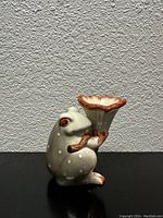 Front view of vintage porcelain frog shaped planter holding a flower pot.