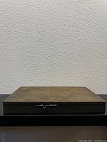 Closed view of vintage flat metal rectangular box with latch.