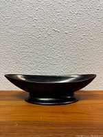 Side view of the black oval bowl showing its shape, size, and finish.
