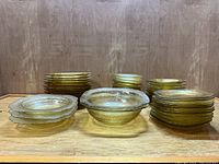 Full lot display from front showing four different dish types including stacks of plates and bowls, all yellow Depression glass with Madrid pattern.