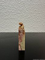 Front side view of the carved Asian soapstone stamp seal showing the figure on top and marbled stone body.