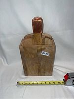 Front view of wooden storage box with three serving boards inside, copper handles visible, measuring tape at base showing width around 7 inches.