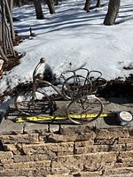 Side view of metal bicycle plant holder showing front, wheels, and basket section with measuring tape beside it for scale (length approx 15 inches).
