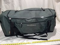Full side view of the green Field & Stream duffel bag showing the logo and front zippered pocket with black straps.