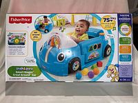Front view of the Fisher-Price Laugh & Learn Smart Stages Crawl Around Car in its original packaging. Shows baby playing with blue interactive car toy with smiling face and dashboard activity features.