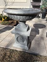 Photo of the concrete planter outdoors on a patio, showing the wide bowl and detailed decorations.