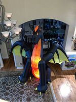 Front view of large inflatable dragon indoors showing lit body and wings