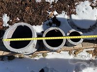 Top-down view showing size variation and internal cavity of the three faux birch planters with measuring tape across largest planter.