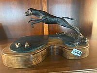 Side view of bronze hunting dog sculpture leaping with wooden base and bronze waterfowl figures