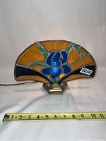 Front view of stained glass light showing blue flower design with measuring tape indicating width about 11 inches.