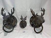 Three metal deer head wall hangers arranged side-by-side against a white backdrop.