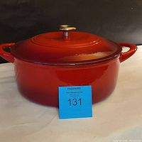 Closed view of the red enameled Dutch oven with lid, showing glossy finish and metal knob on lid.