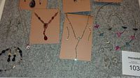 Full lot showing various costume jewelry pieces on felt countertop including earrings, necklaces, bracelet, and watch.
