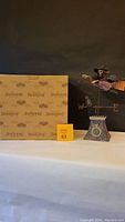 Photo showing the Jim Shore branded original box and the weather vane figurine with witch flying on broomstick.