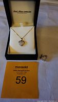 Fred Meyer Jewelers necklace in black box with gold heart pendant on 18-inch chain and additional heart pendant on paper with auction tag