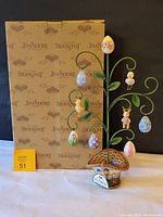 Jim Shore Easter tree with original box, front view showing the full tree with hanging eggs and animal figures, placed in front of the box.