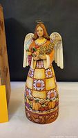 Front view of the angel figurine showing detailed quilt pattern dress, cornucopia, and harvest motifs.