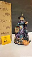 Front view of Jim Shore Halloween witch figurine with original packaging visible in background.