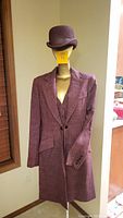 Berry/plum linen weave equestrian coat and matching hat on mannequin in natural light by window.