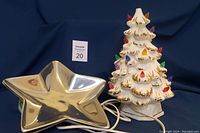 Photo showing star-shaped stainless steel plate and lit ceramic Christmas tree with colorful bulbs and gold accents.