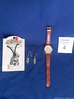 Full set on blue cloth showing watch with brown leather band, pewter pendant still on original display card, and pewter earrings.