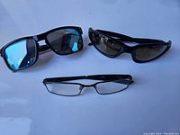 Three pairs of Oakley glasses shown together - 2 sunglasses and 1 prescription frame.