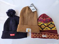 Three winter hats displayed together on a white surface showing all hats clearly in the lot