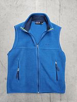 Front view of medium sized blue Patagonia Synchilla fleece vest with zipper and pockets on concrete floor.