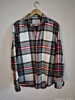 Full view of the Portuguese Flannel shirt showing a multi-color plaid pattern with white, black, red, pink, yellow, and teal, button-up front and collar.