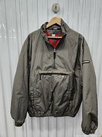 Front view of the gray vintage Tommy Hilfiger pullover jacket on a hanger, showing elastic cuffs and front pocket.