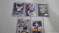 Photo showing 5 Alex Ovechkin hockey cards in protective sleeves, distinct designs visible