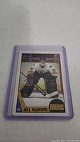Front view of Bill Ranford rookie hockey card in purple protective sleeve showing player in goalie attire for Boston Bruins.