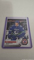 Photo of Elias Pettersson rookie hockey card in purple protective sleeve, showing front of card with player in Canucks uniform.