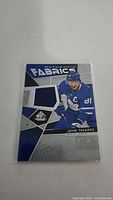 Photo showing the front of the SP Authentic Authentic Fabrics card featuring John Tavares in Maple Leafs uniform with multiple blue fabric swatches embedded.