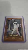 Photo of a Jose Bautista rookie baseball card in a protective sleeve with brown border and Topps branding.