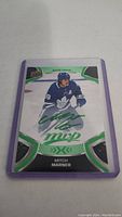 Hockey card featuring Mitch Marner of Toronto Maple Leafs, signed in green ink with MVP inscription, in purple protective sleeve.