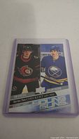 Photo of a single hockey trading card featuring Tim Stutzle and Dylan Cozens in Young Guns Series Two Checklist 451-500, sleeved in a clear plastic protective holder.