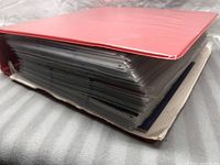 Side view of one red binder fully packed with hockey card sleeves.