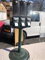 Complete view of the 3 slot bubble gum machine on green stand showing base and coin slots.