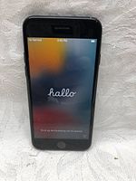 Front view of black Apple iPhone 7 showing the welcome screen in Dutch ('hallo'), indicating the phone powers on and is in initial setup mode.