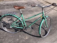 Full side profile of mint green Linus Mixte 3-speed bicycle showing saddle, fenders, chainring and rear rack